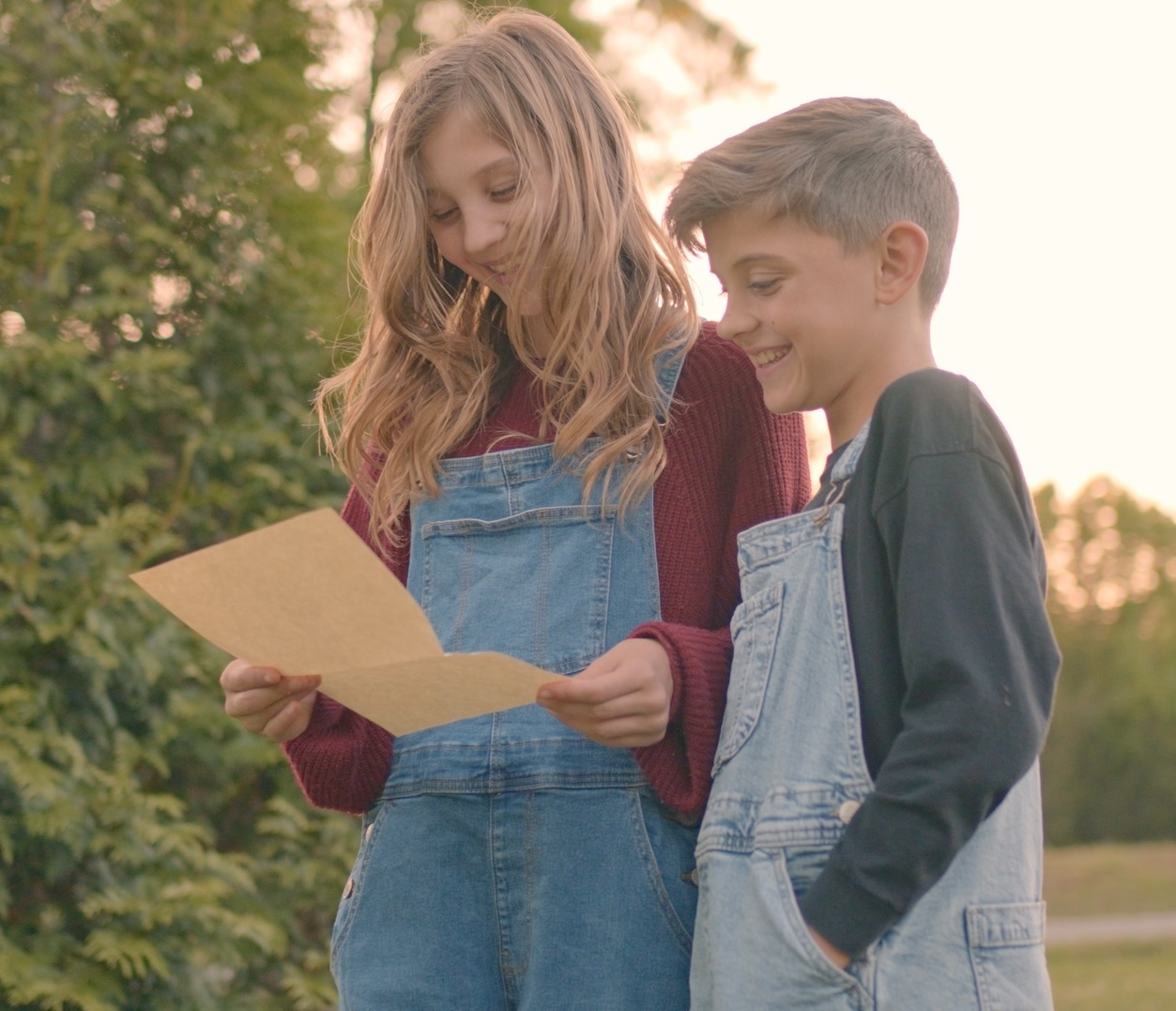 Children reading a Little Red Mailbox letter outdoors